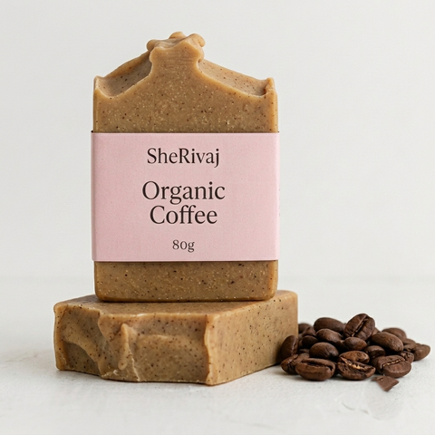 Two bars of SheRivaj soap with a small bowl of coffee grounds on a white background